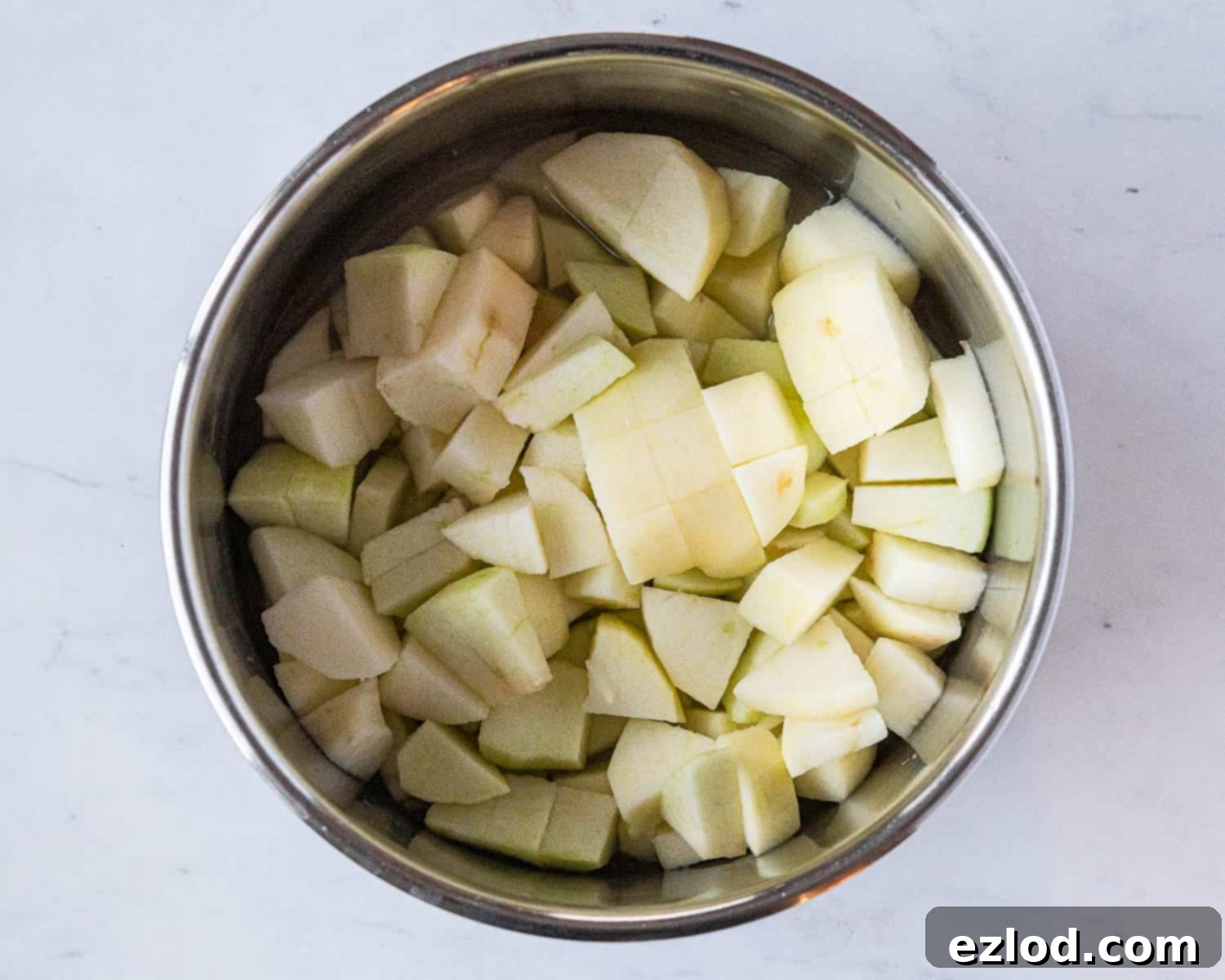 Diced cooking apples prepared with lemon juice and water in a saucepan, ready for the first step of making vegan apple curd.
