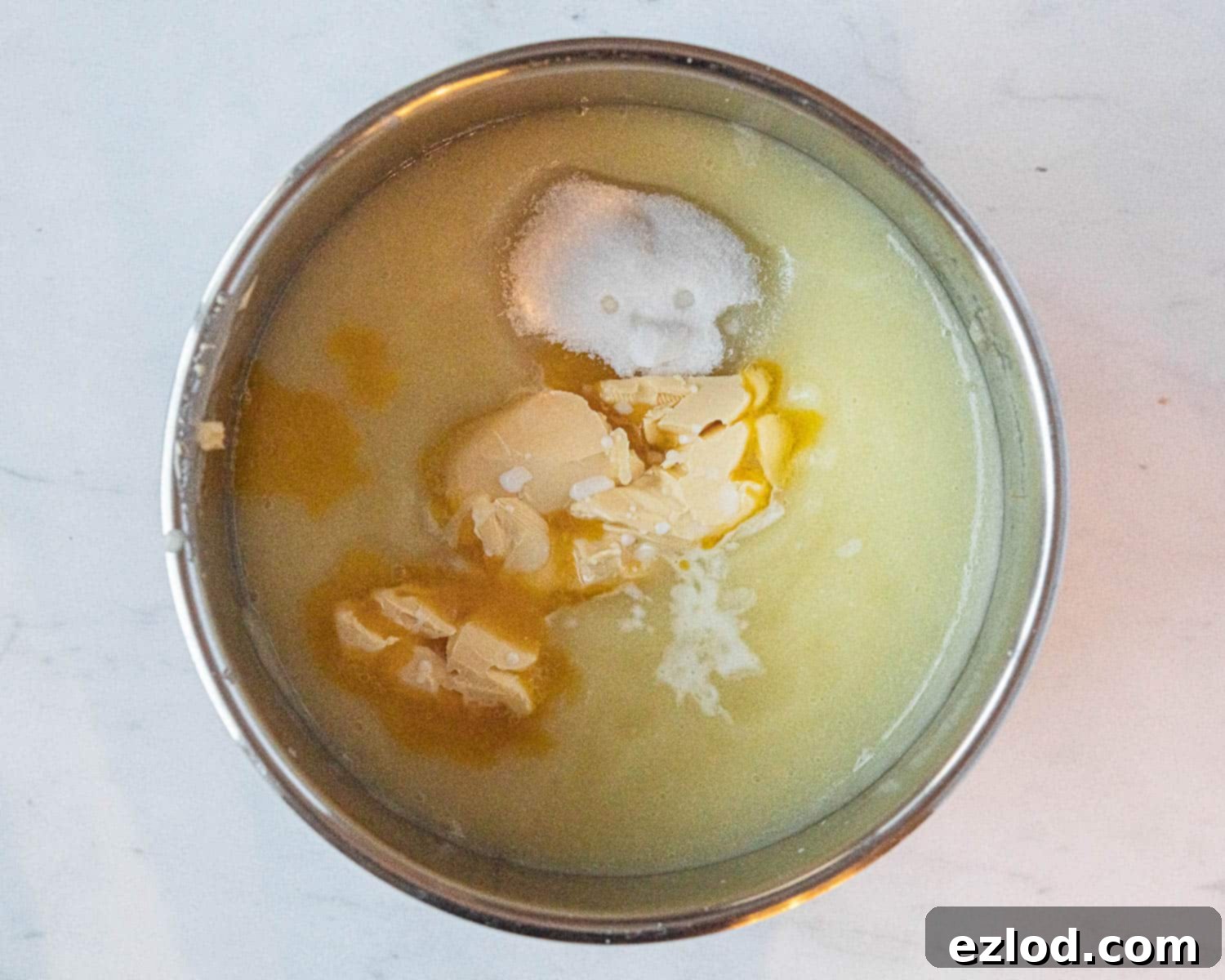 Vegan butter, sugar, and cornflour slurry being added to the blended apple mixture in a saucepan, ready for whisking.