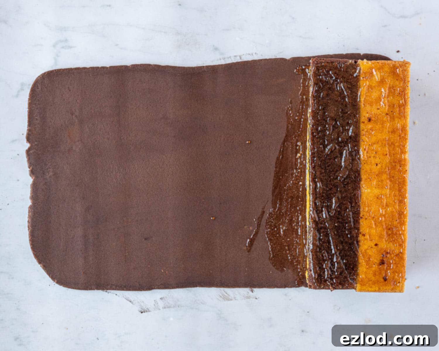 Decadent Vegan Chocolate Orange Battenberg 12 Step 8: The marmalade-covered cake positioned on top of the rolled-out marzipan, ready for wrapping.
