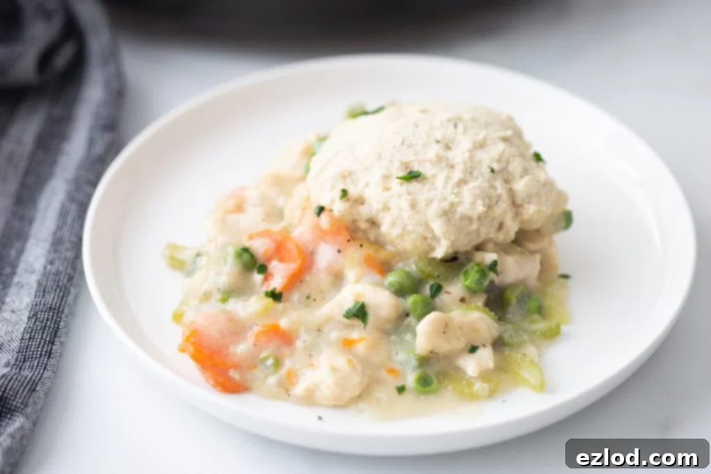 A hero shot of Gluten-Free Chicken Pot Pie on a white plate with a grey striped napkin to the left side.