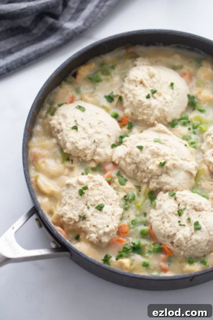 Overhead view of a healthy chicken pot pie in a skillet with a homemade biscuit topping and fresh parsley garnish.