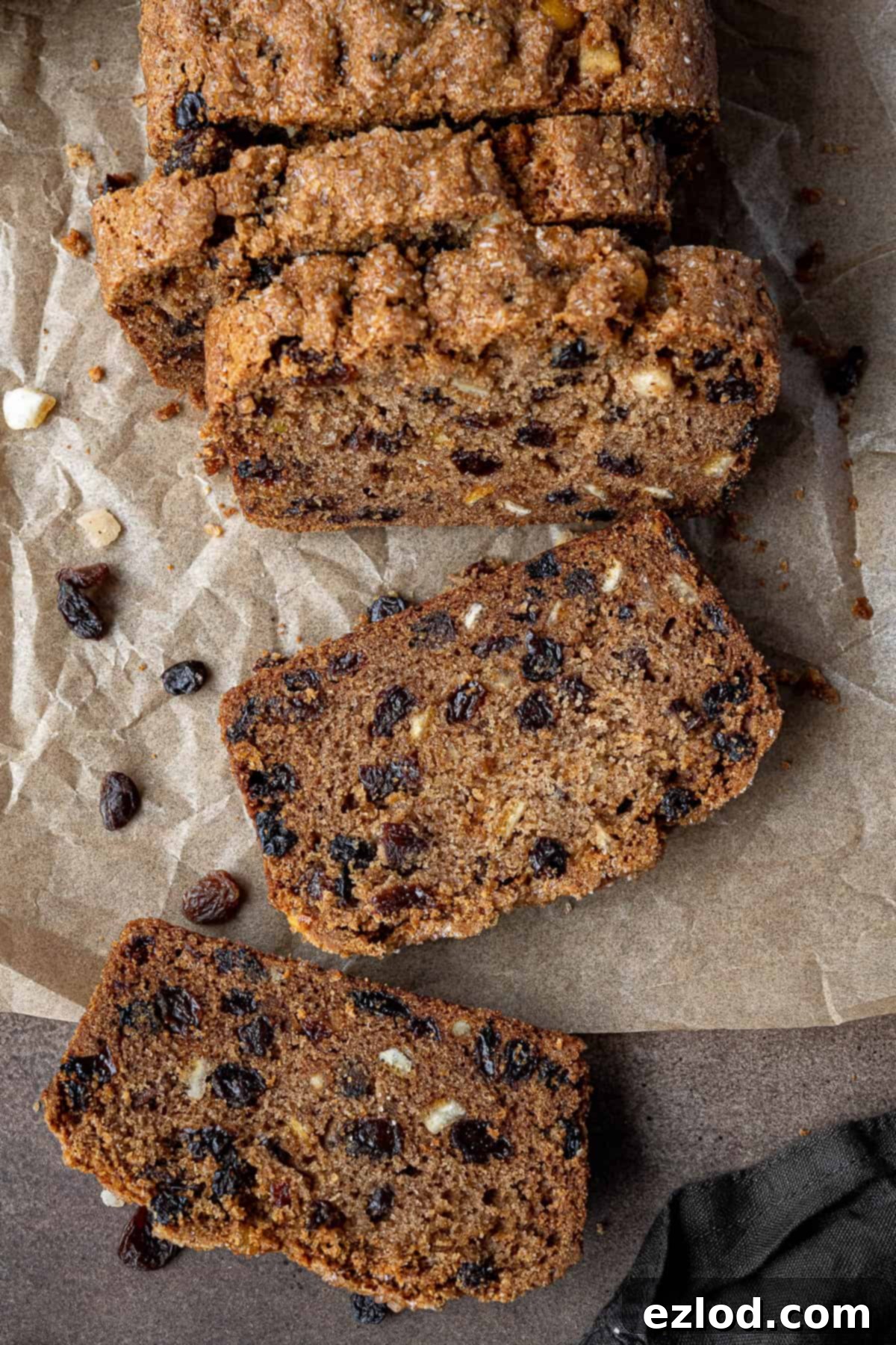 Close up of a slice of vegan fruit cake loaf, showing the distribution of dried fruit and moist texture.