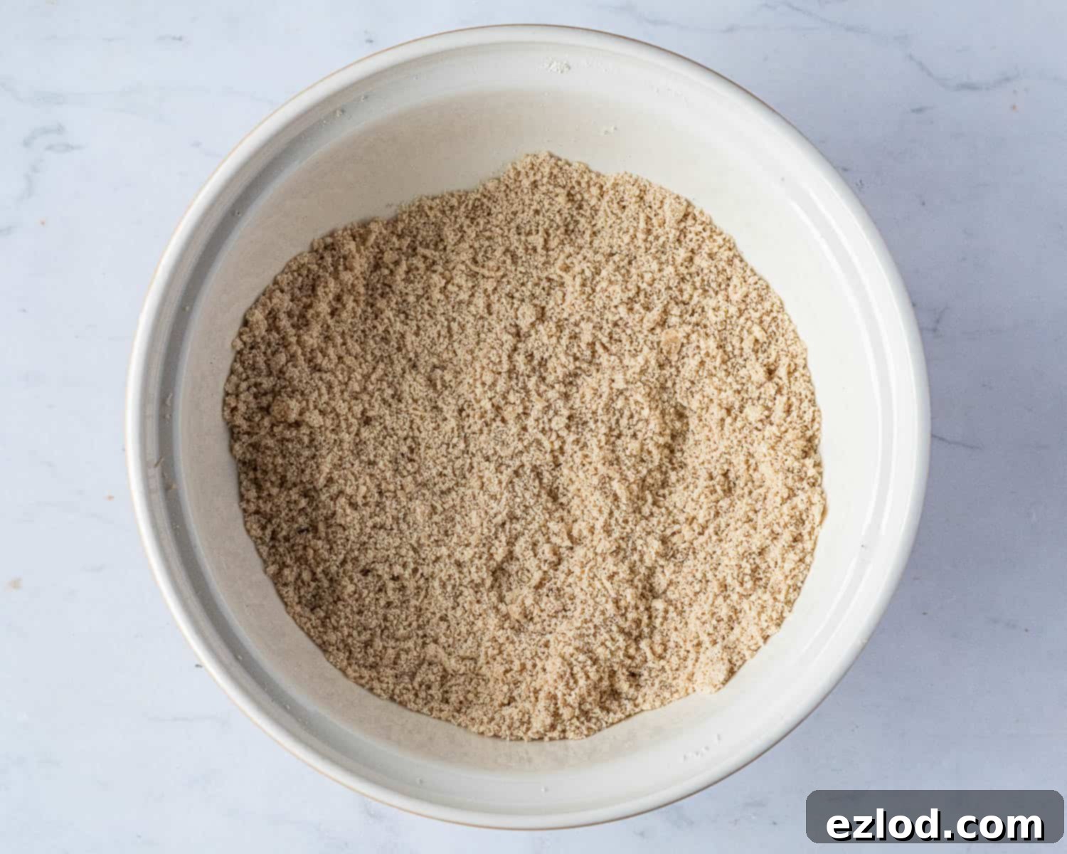 Step 1: Vegan butter being rubbed into dry ingredients, creating a fine breadcrumb-like mixture.