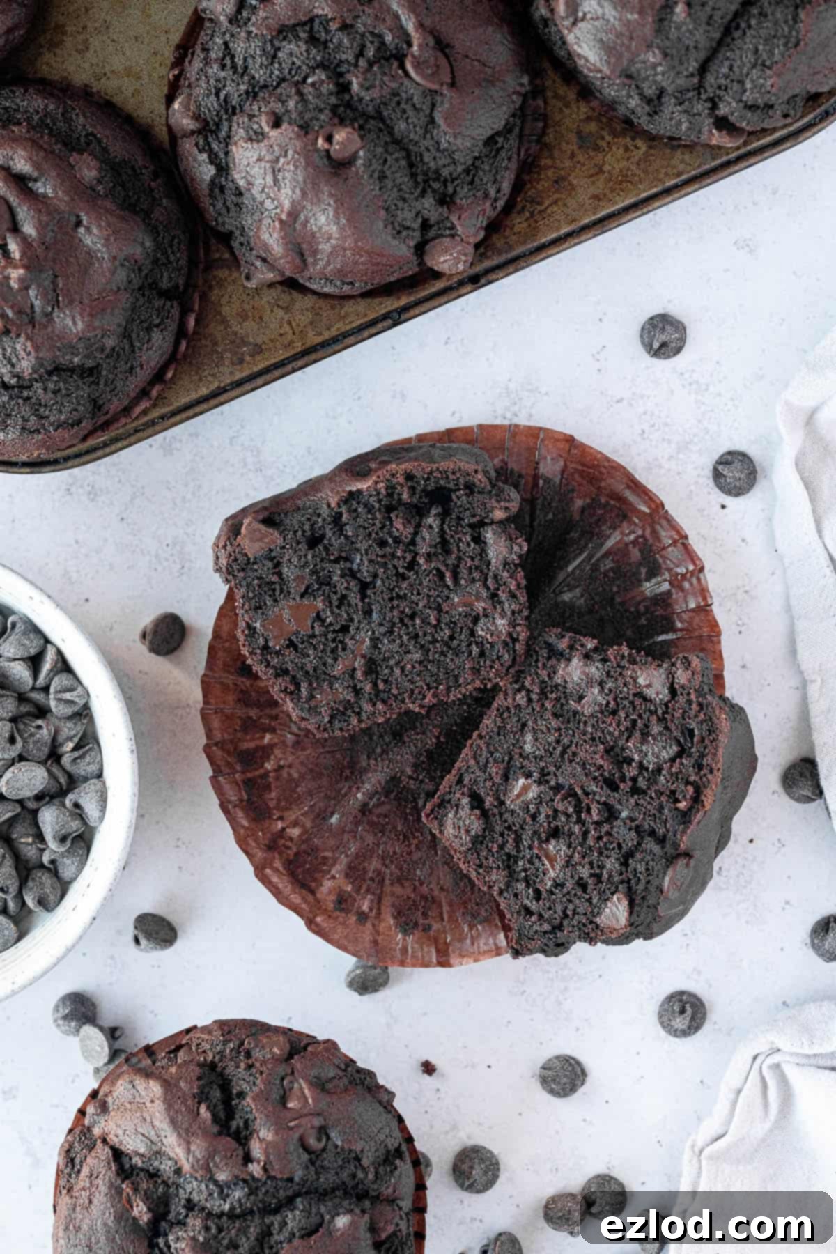 A vegan double chocolate muffin sliced in half, revealing its moist interior and generous chocolate chips.