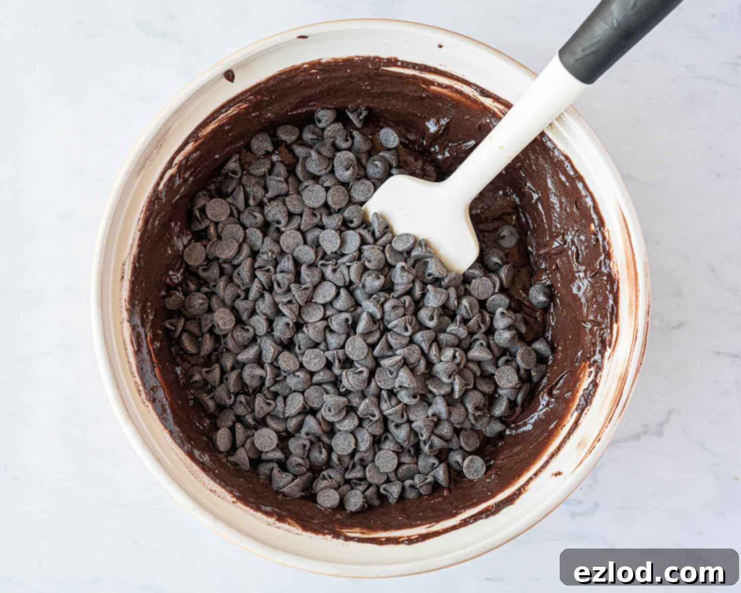 Step 4 in making vegan double chocolate muffins: gently adding the chocolate chips to the batter.