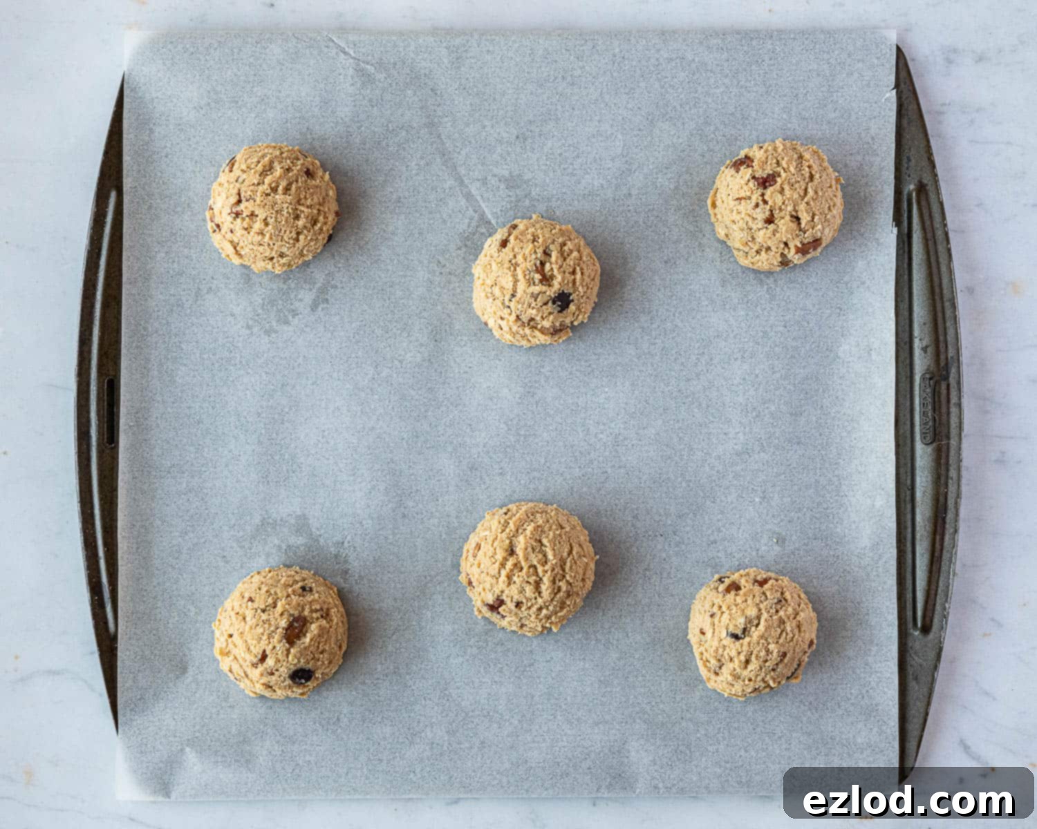 Step 5: Portioned out balls of vegan peanut butter oatmeal cookie dough, evenly spaced on a parchment-lined baking sheet.