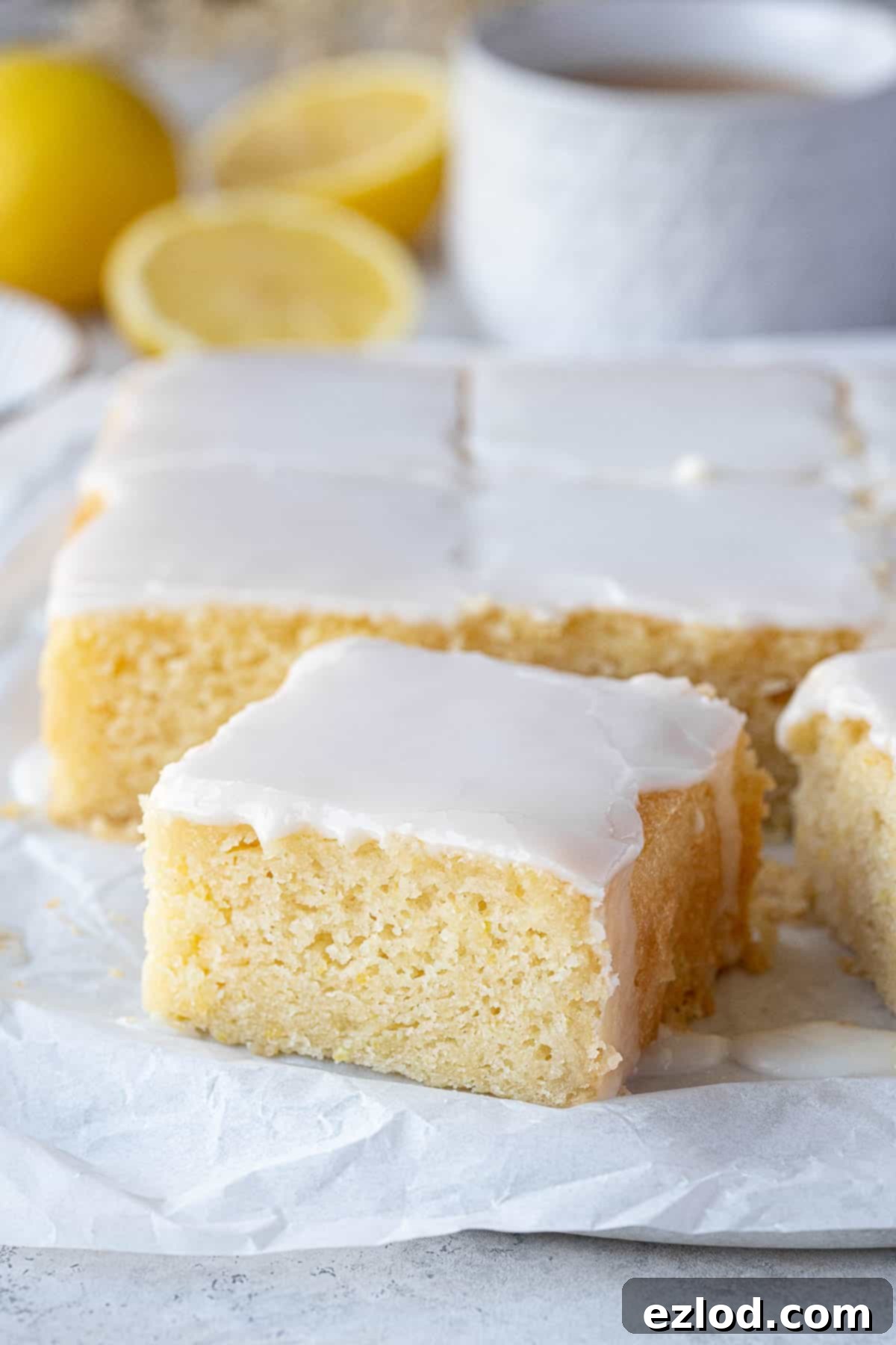 A close-up view of a perfectly moist square of gluten-free vegan lemon drizzle cake, showcasing its delicate crumb and glistening glaze.