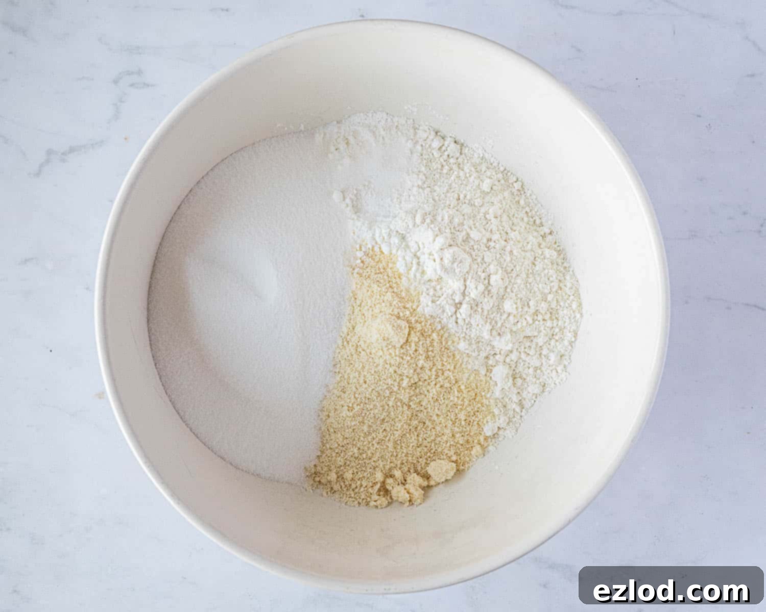 Step 1 in making gluten-free vegan lemon drizzle cake: A close-up of a bowl filled with perfectly combined dry ingredients.