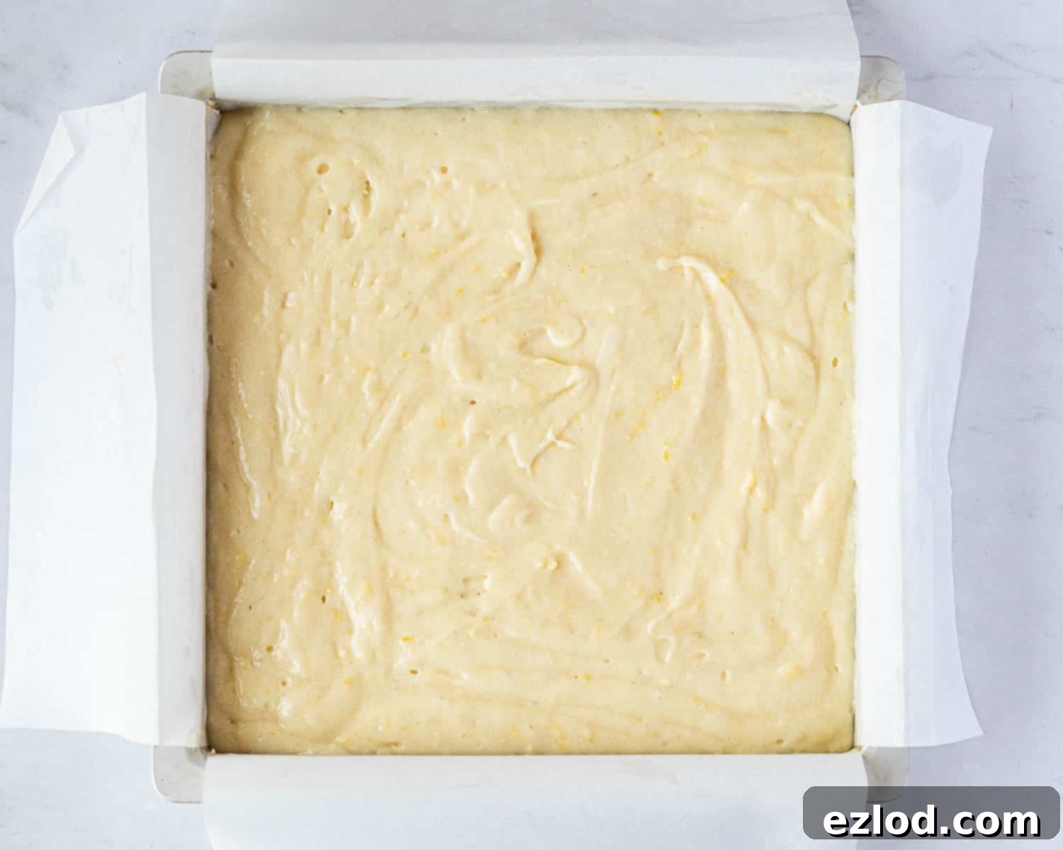 Step 3 in making gluten-free vegan lemon drizzle cake: The smooth cake batter precisely poured and levelled in the prepared square baking tin.