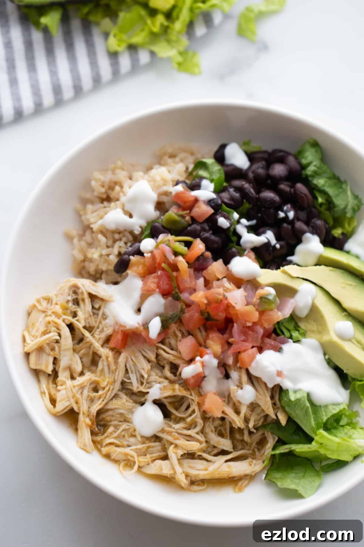 Effortless Salsa Verde Chicken Instant Pot or Slow Cooker 3 A close-up shot of a healthy salsa verde chicken burrito bowl with fresh toppings like Greek yogurt, brown rice, pico de gallo, and avocado, ready to be enjoyed.