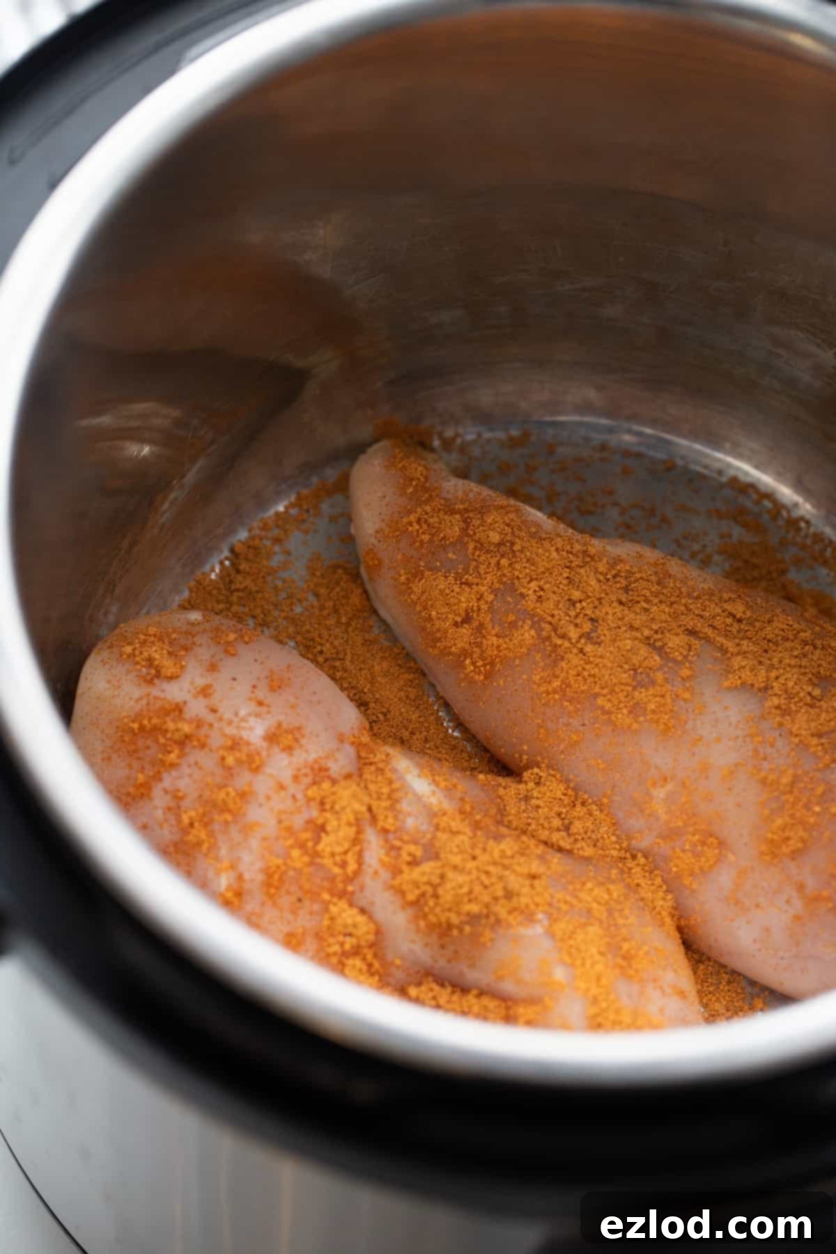 Effortless Salsa Verde Chicken Instant Pot or Slow Cooker 5 The inner pot of an Instant Pot holding raw chicken tenders generously seasoned with a salt-free taco spice blend.