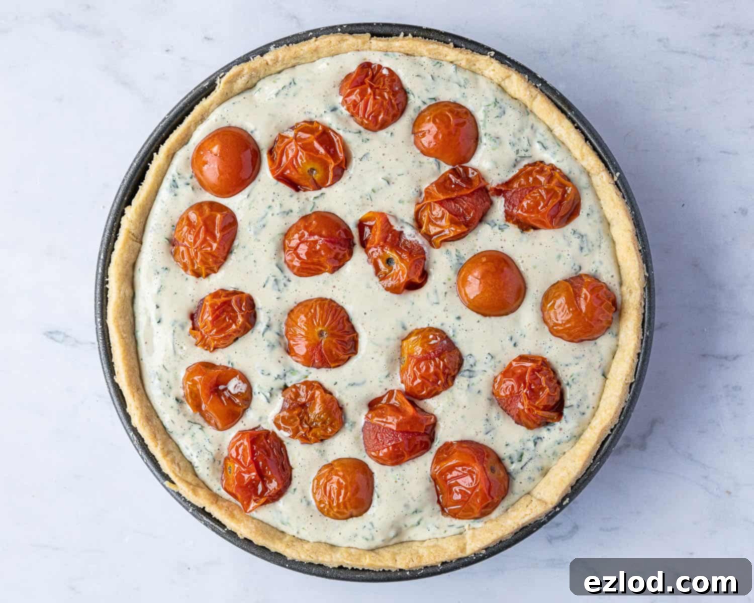 Step 9: The vegan quiche assembled in its pastry case, with filling and tomatoes, ready for baking.