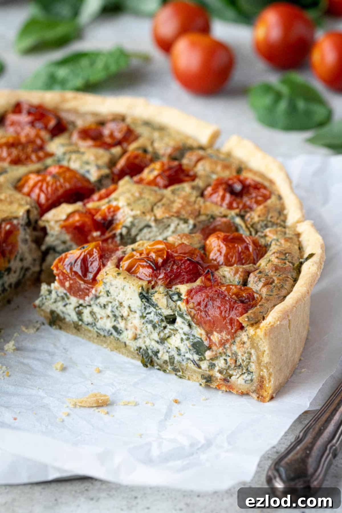 A close-up view of a perfect slice of vegan tomato spinach quiche, showcasing its creamy texture and vibrant filling.