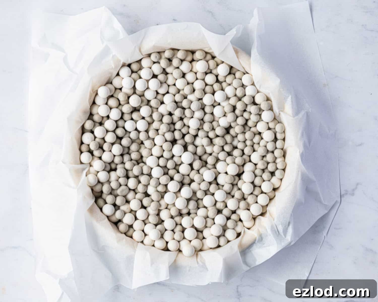 Step 4: The pastry case is lined with baking parchment and filled with baking beans for blind baking.