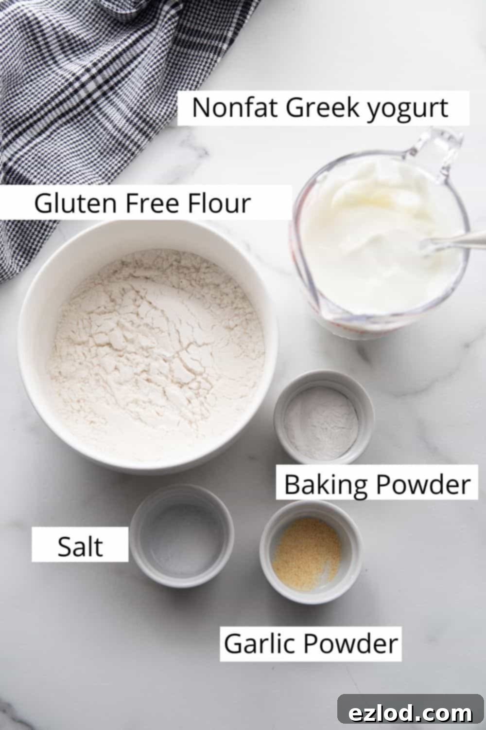Creamy Hot Honey Ricotta Pizza 3 Ingredients laid out for gluten-free Greek yogurt pizza crust: a bowl of gluten-free flour, a tub of Greek yogurt, baking powder, salt, and garlic powder.