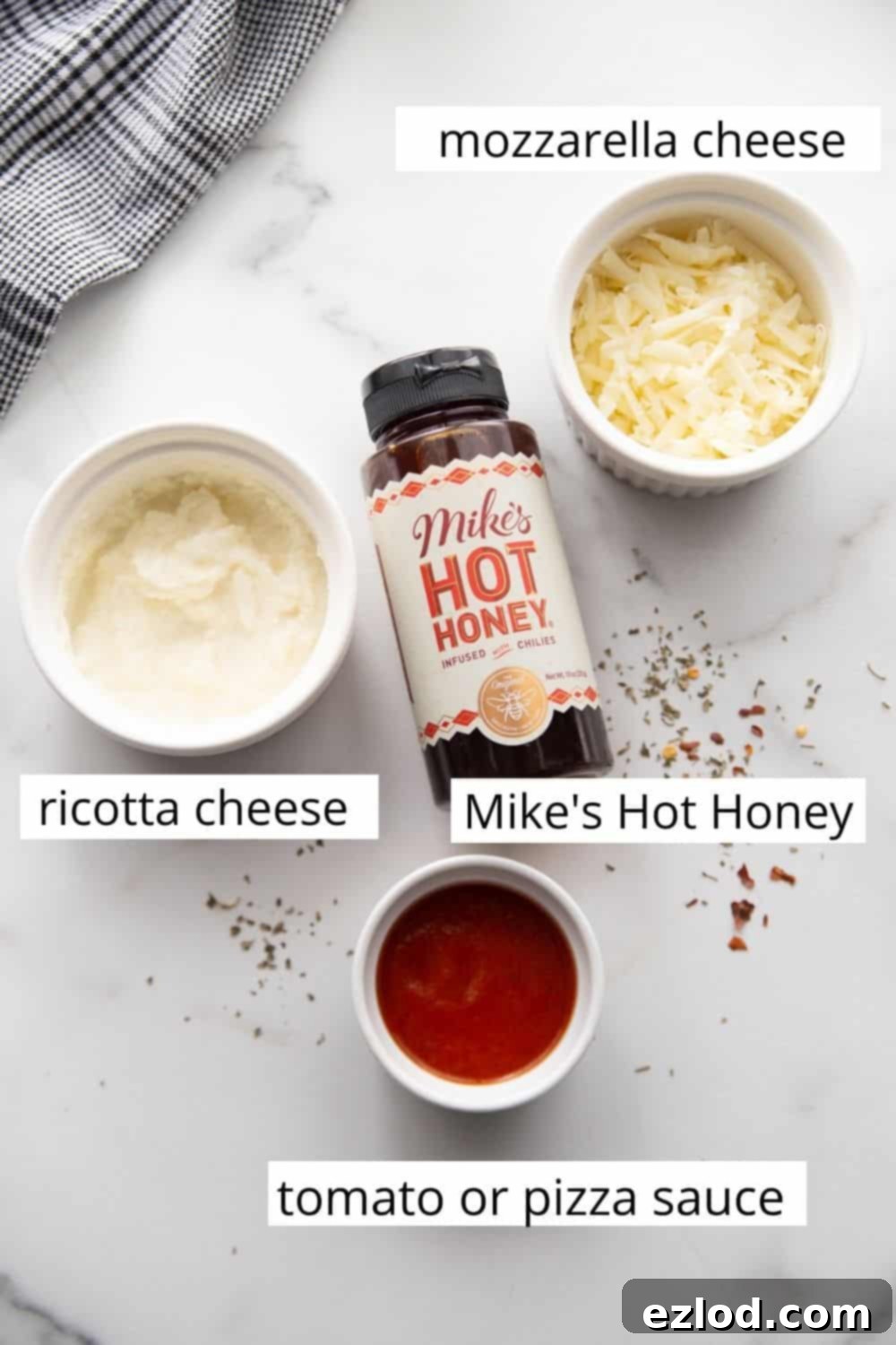 Creamy Hot Honey Ricotta Pizza 4 Pizza toppings for Hot Honey Pizza: a bowl of vibrant tomato sauce, creamy ricotta cheese, shredded mozzarella cheese, and a bottle of Mike's Hot Honey.