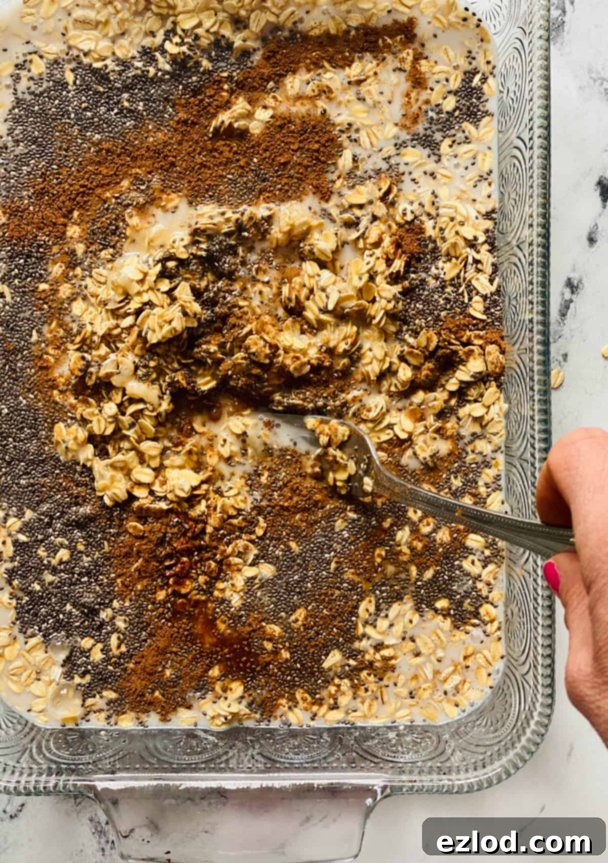 A fork gently stirring the wet and dry ingredients together in the baking dish, creating a uniform mixture. 