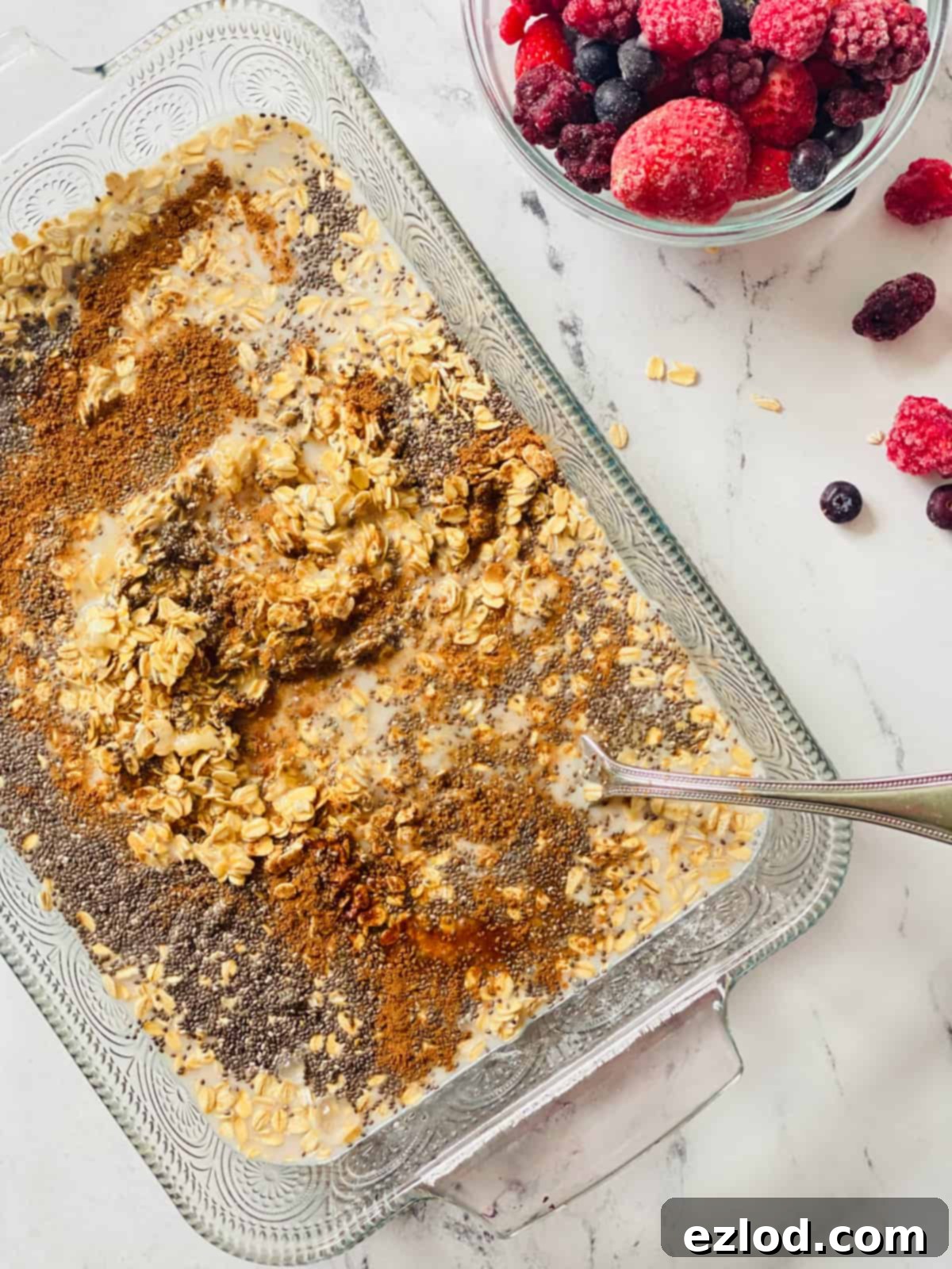 Frozen mixed berries are carefully spread on top of the banana oat mixture in the baking dish before baking. 