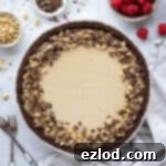 Vegan peanut butter pie surrounded by bowls of raspberries, peanuts and chocolate shavings.