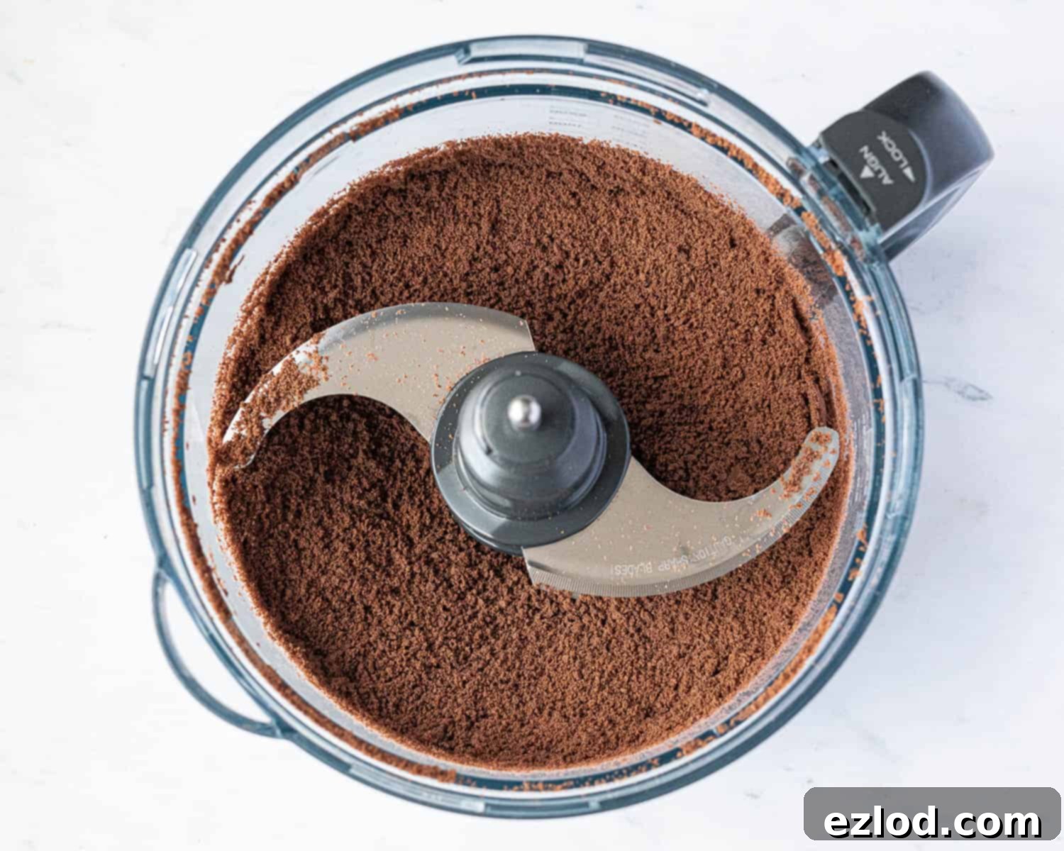 Step 1 in making vegan peanut butter pie: finely crushed chocolate cookie crumbs are visible inside a food processor bowl, demonstrating the perfect texture required for the crust.