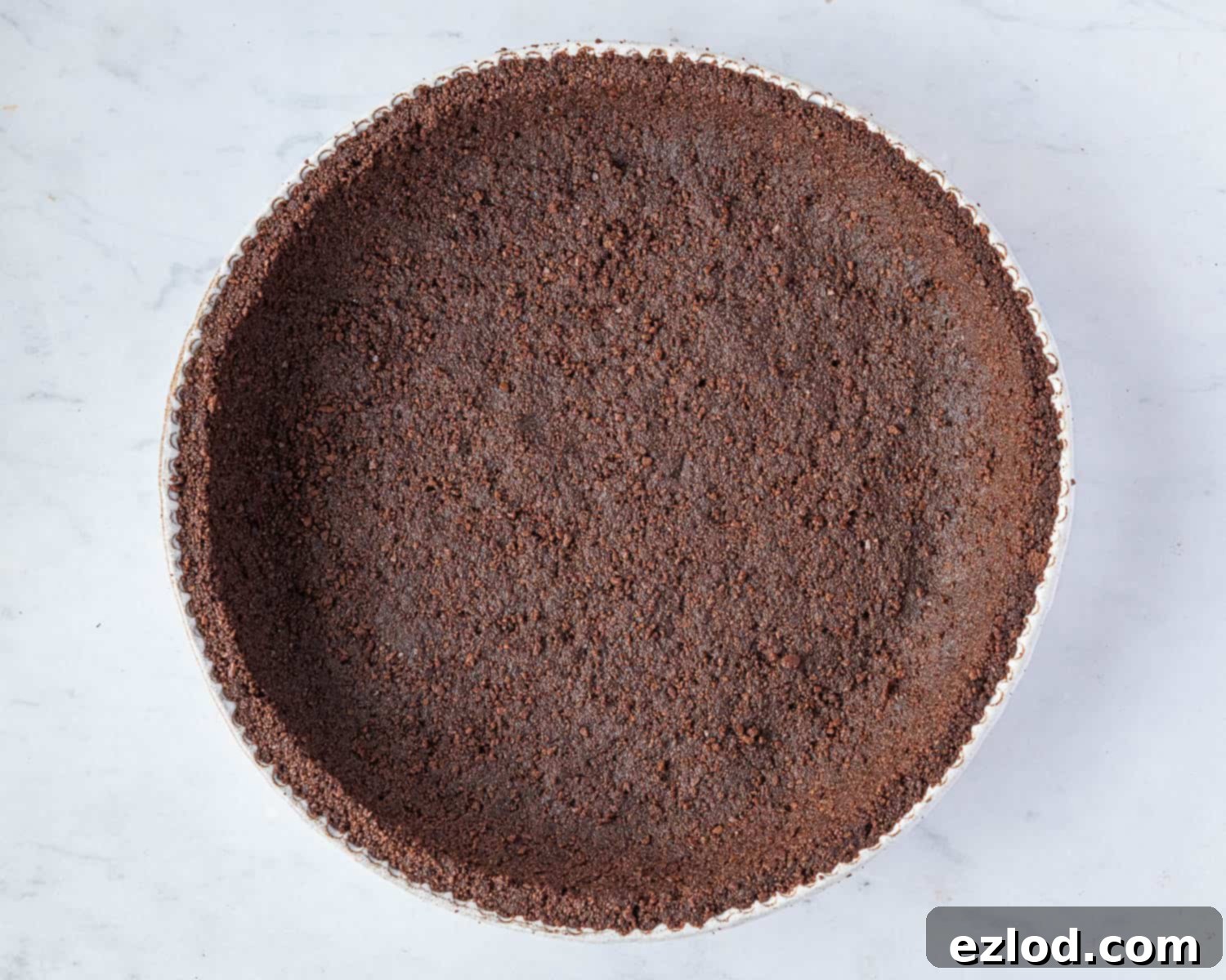 Step 3: The chocolate cookie crust is expertly pressed into a pie dish, with crumbs forming a solid base and extending up the sides, ready for its crucial chilling period in the freezer.