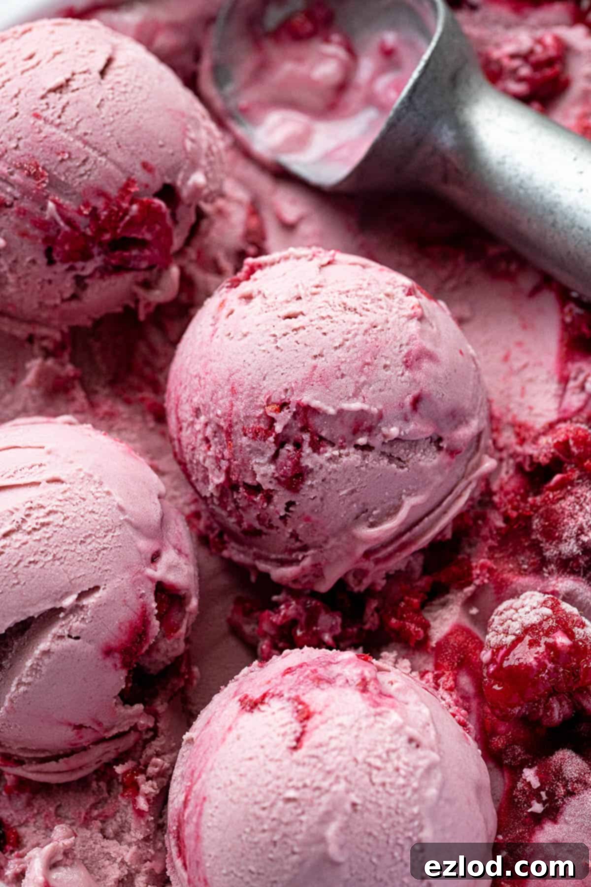 Close up of scoops of vegan raspberry ice cream with fresh raspberries.