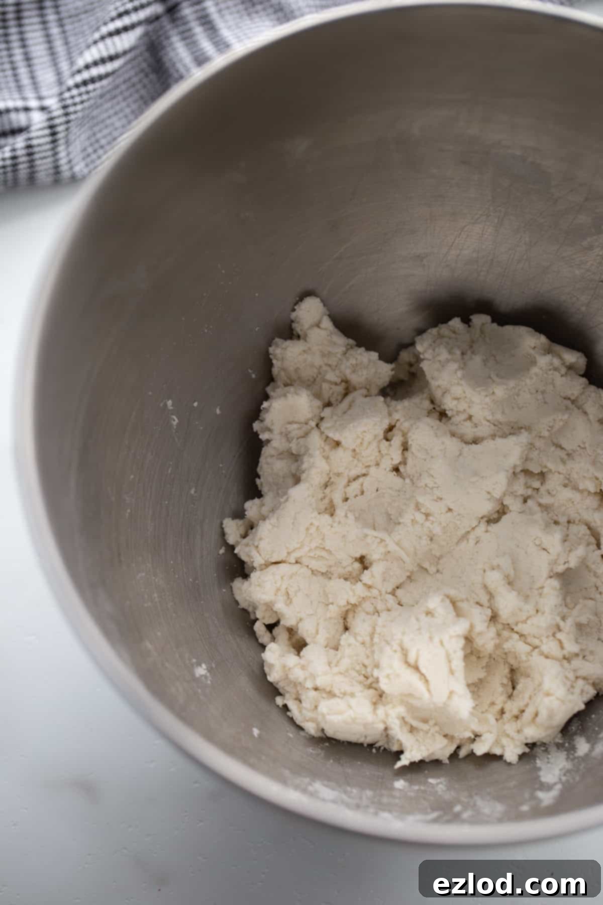 An overhead shot showing gluten-free Greek yogurt pizza dough being mixed in a stand mixer, forming a soft, cohesive ball.