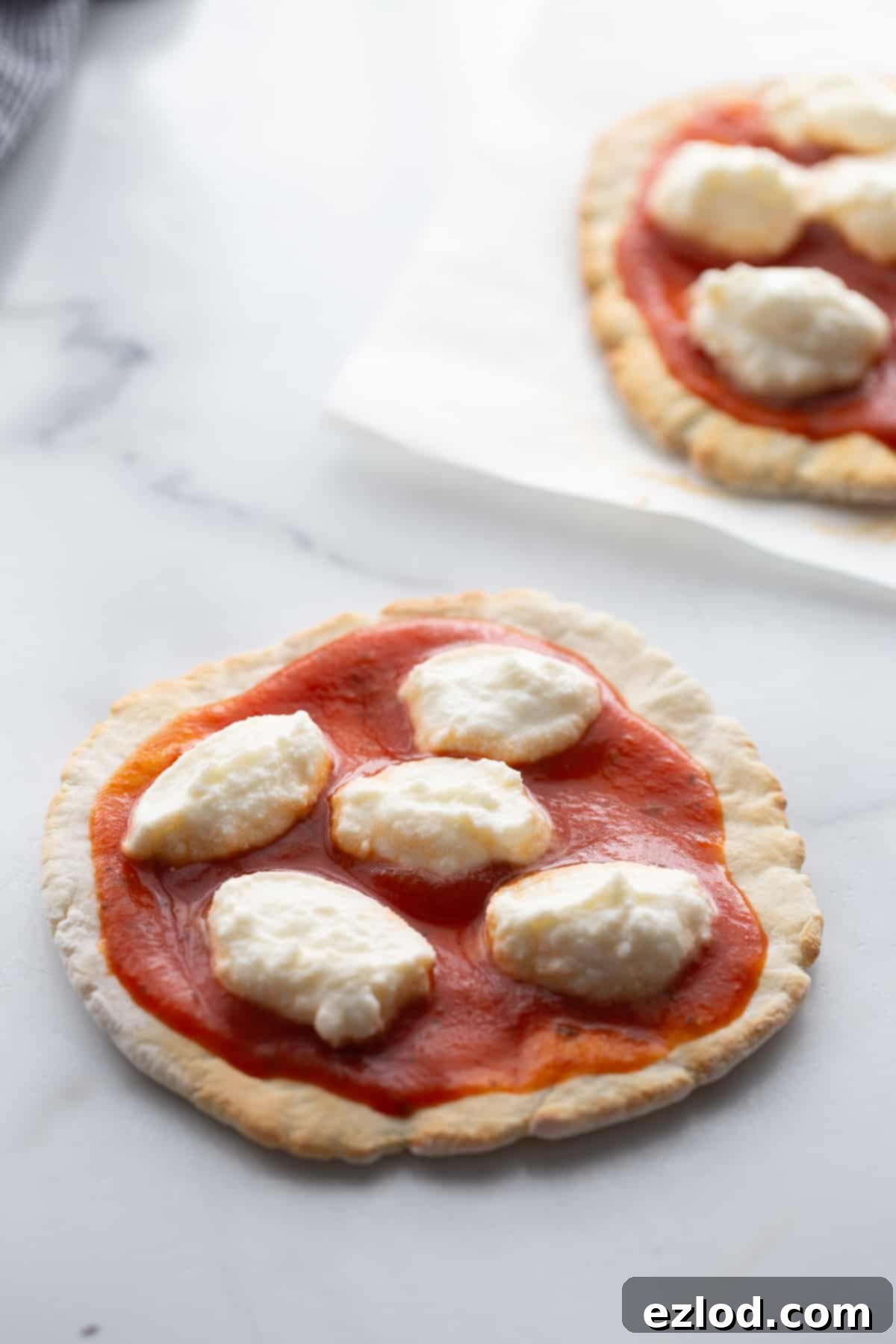 A personal-sized gluten-free pizza, lavishly topped with rich ricotta cheese and vibrant tomato sauce, showcasing its delicious potential.