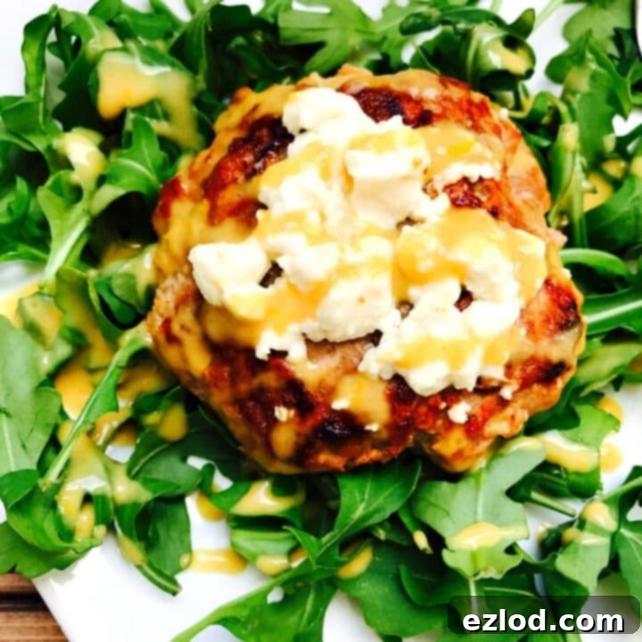Gourmet Turkey Burgers with creamy goat cheese and a bright citrus maple dijon sauce, served on a bed of fresh arugula