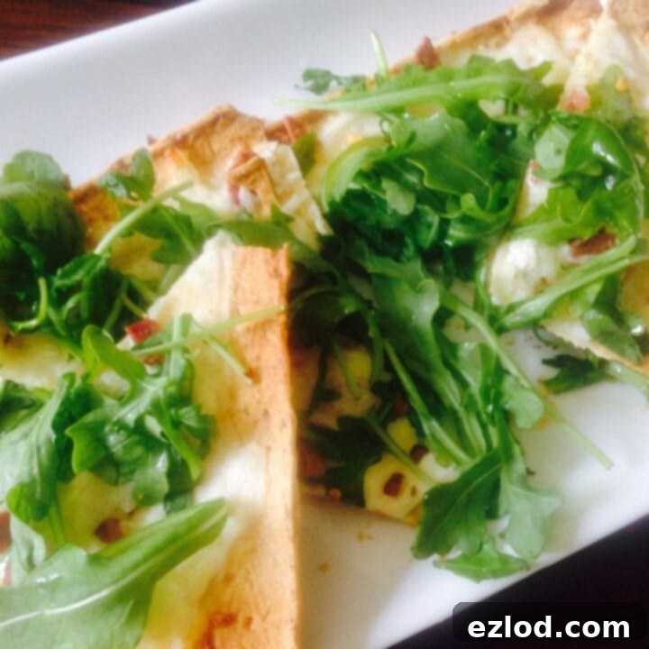 Three Cheese White Pizza with Arugula, featuring ricotta, mozzarella, and parmesan on a thin crust