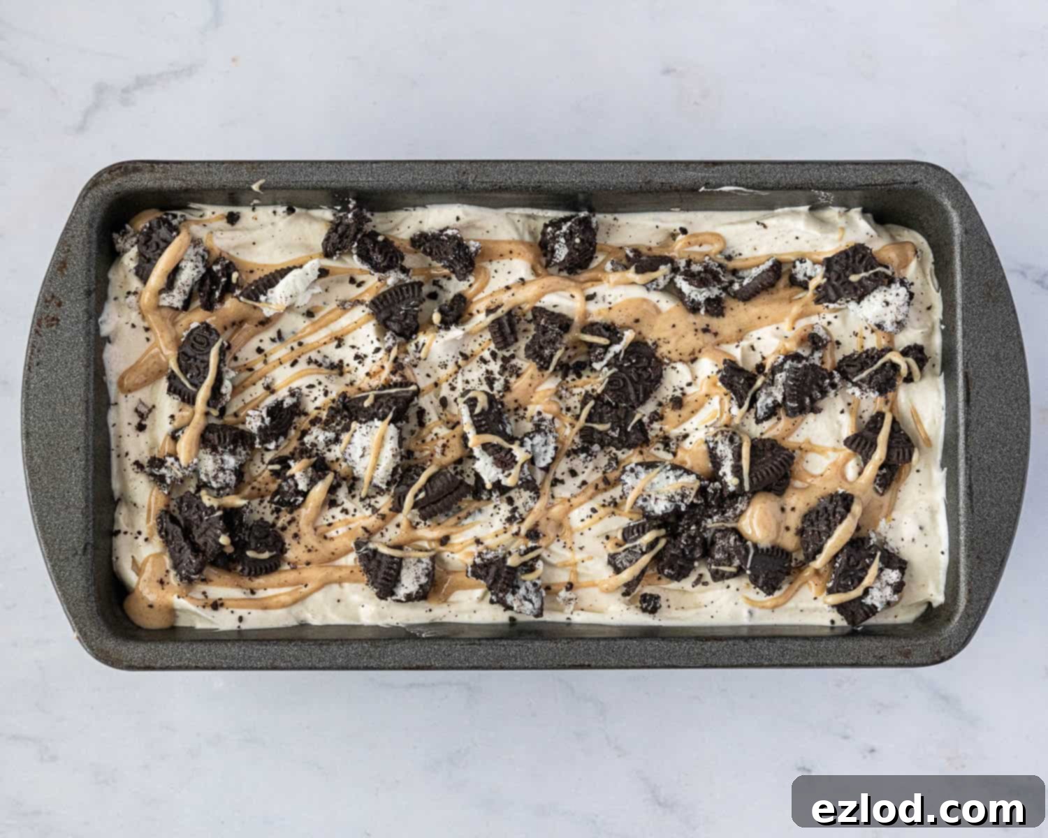 The ice cream in a loaf tin topped with Oreos and peanut butter.