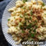 Close up of a plate of vegan spaetzle with cheese sauce and crispy fried onions.