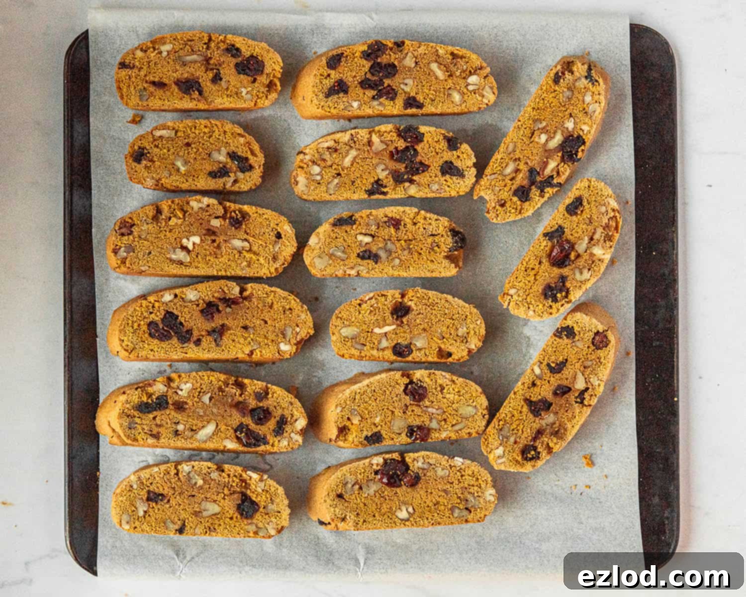 Freshly twice-baked vegan pumpkin biscotti slices arranged on a baking sheet.