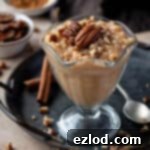 Vegan pumpkin rice pudding topped wiith pecans in a dessert glass on a metal tray.