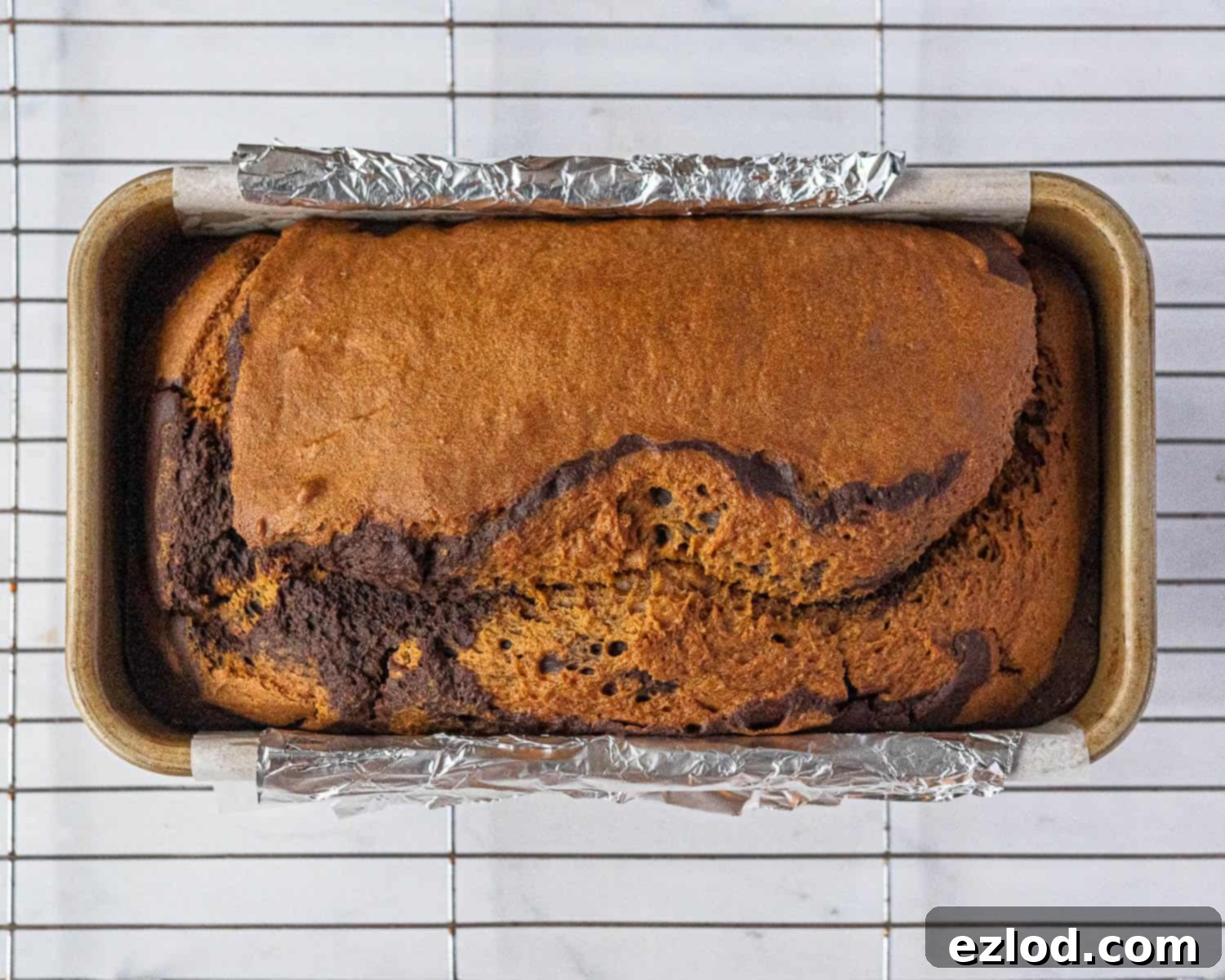 Step-by-step image of the fully baked pumpkin chocolate marble bread in the loaf tin, golden brown and ready to cool.