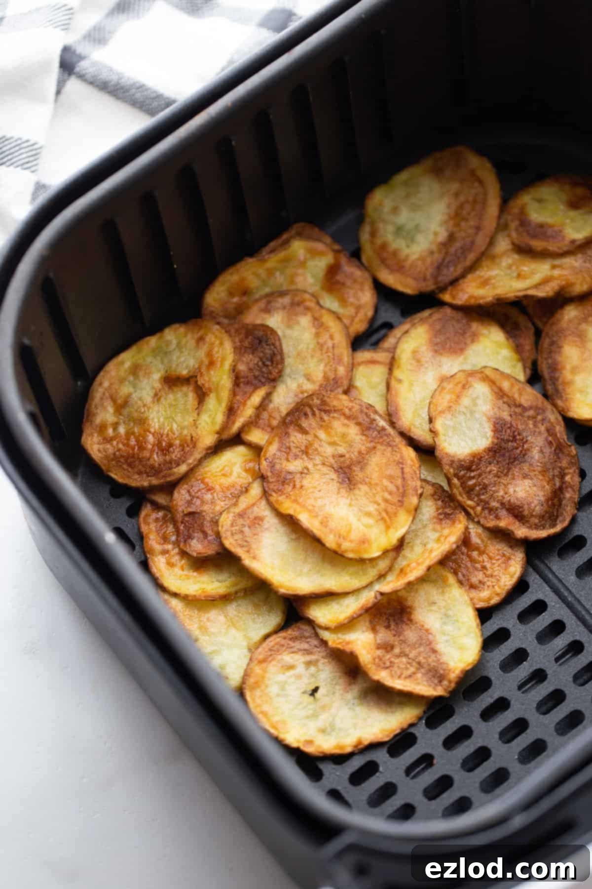 Crispy golden homemade potato chips in an Air Fryer basket, perfectly air-fried for a healthy snack option.