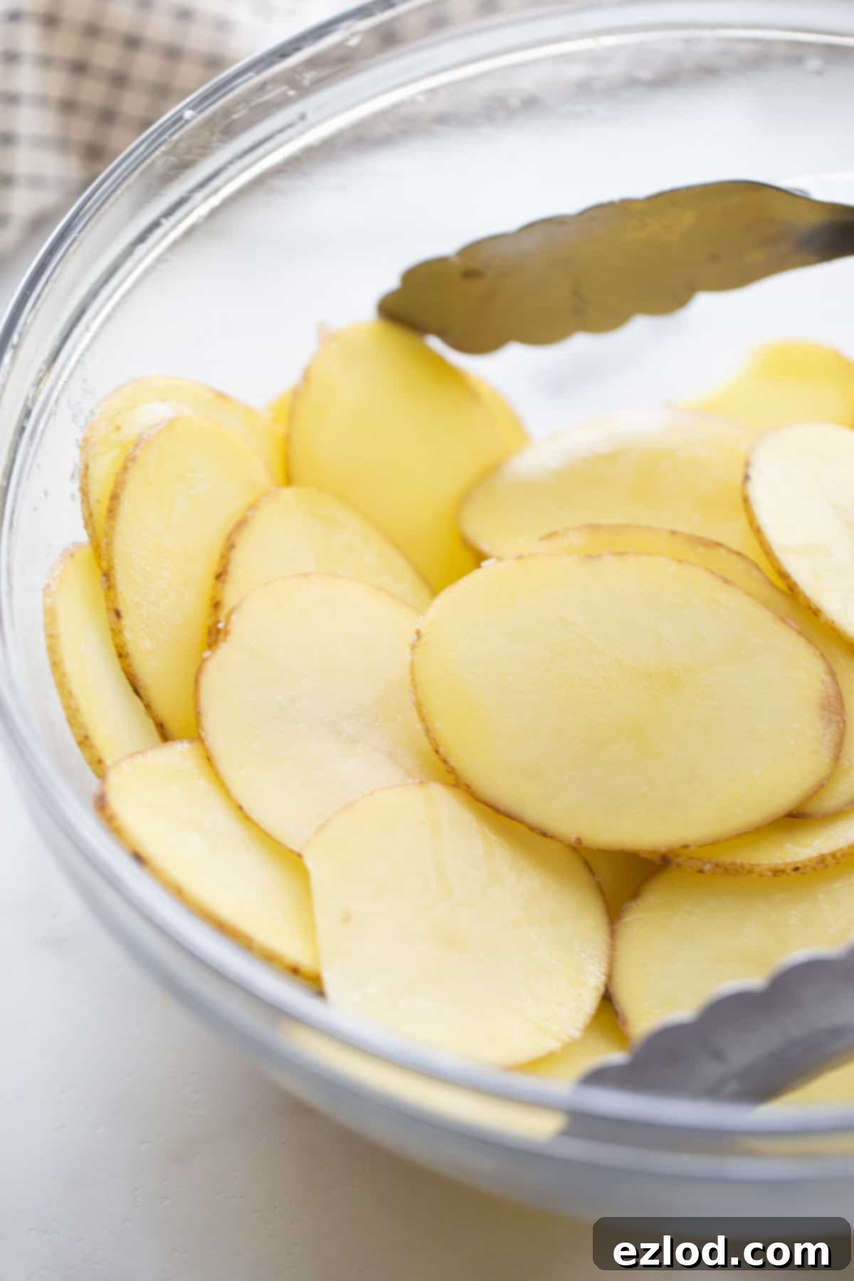 Drained and dried potato slices spread out on paper towels, ensuring all moisture is removed before air frying.