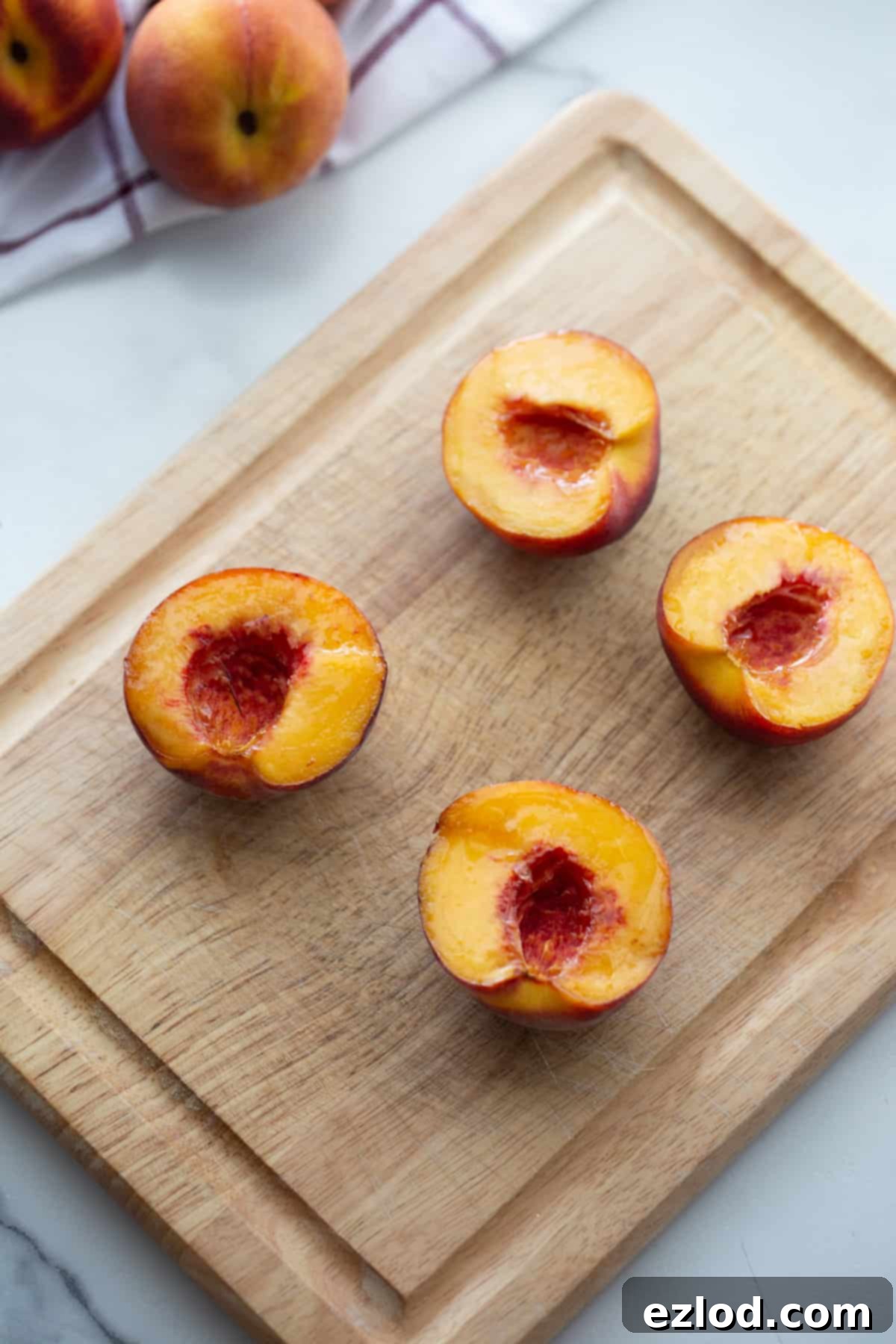 Sweet Air Fried Peaches with Creamy Ricotta 4 Four peach halves on a table sitting on a cutting board