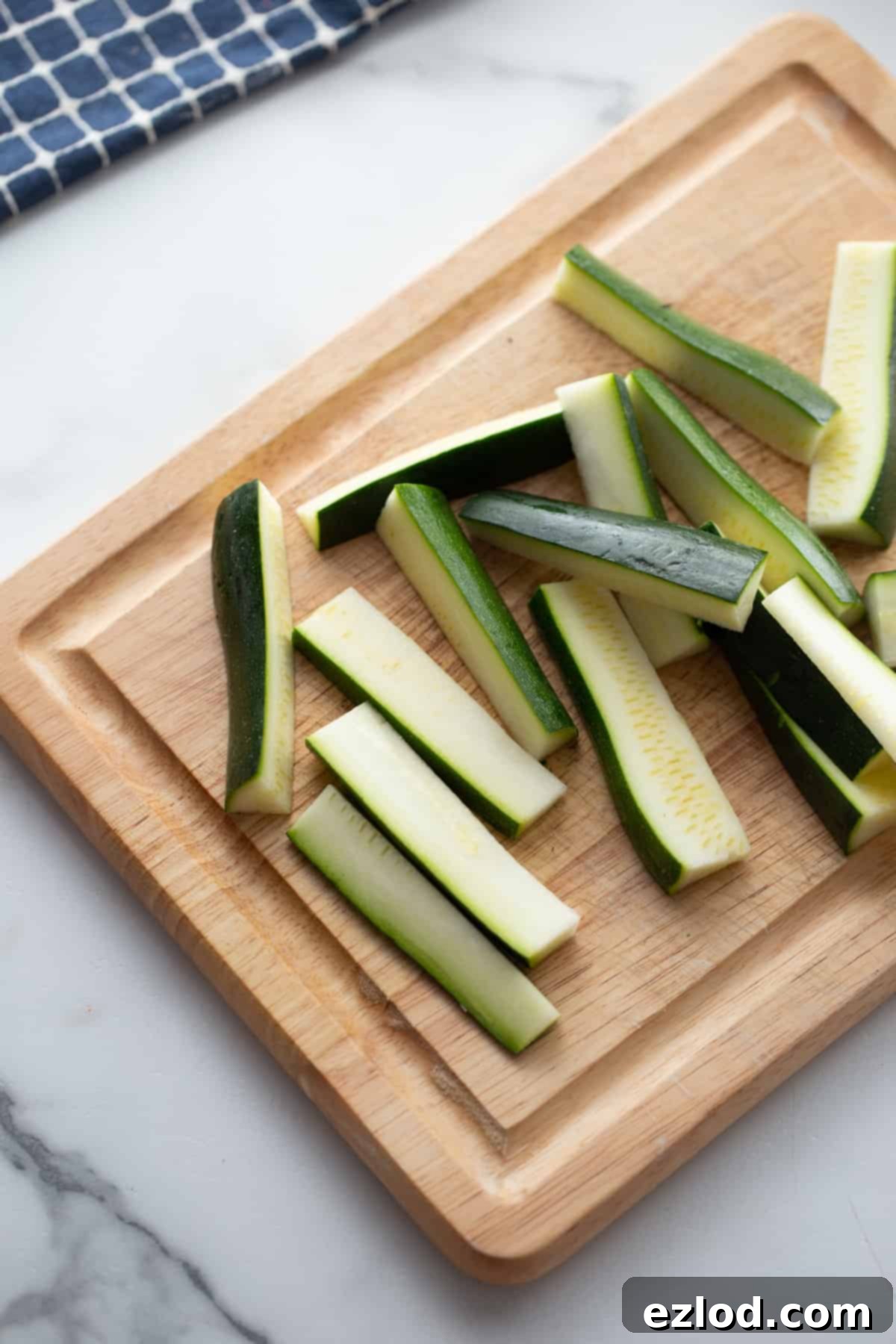 zucchini on a cutting board sliced into matchsticks or fries