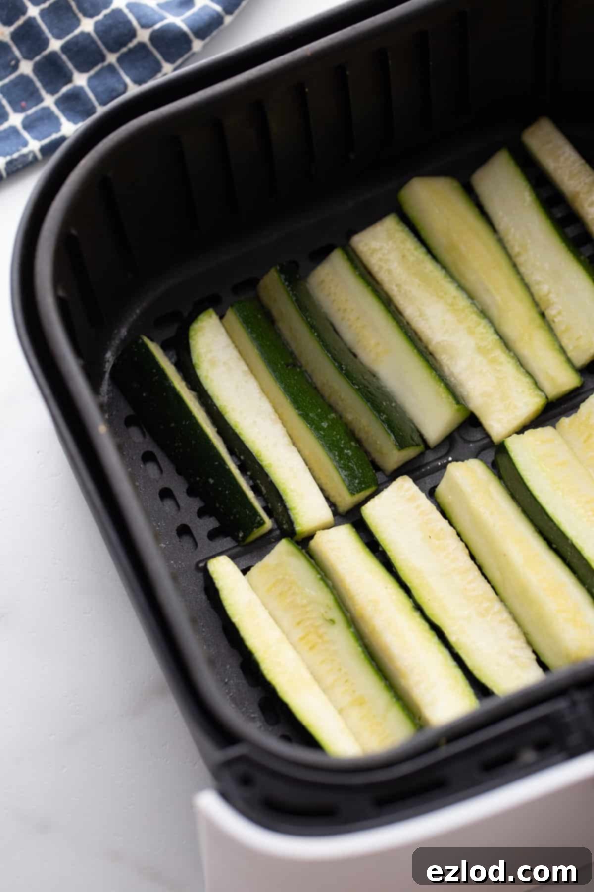 Zucchini cut into fry shapes inside of an air fryer