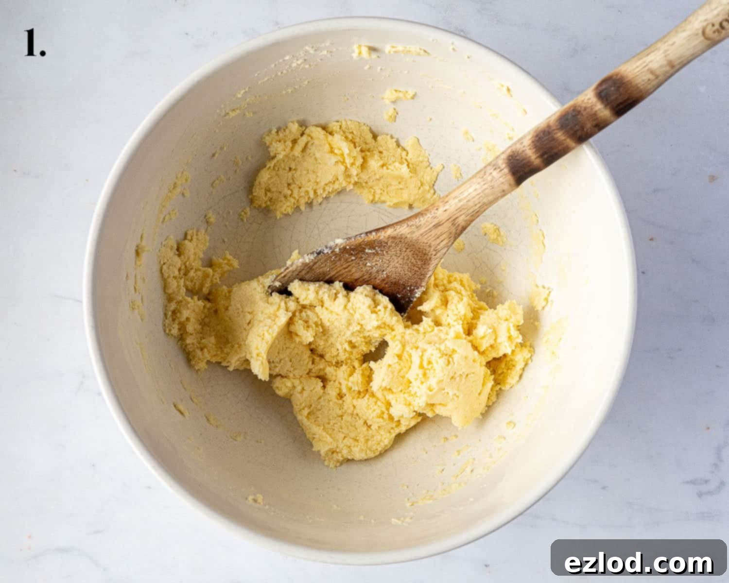 Step 1 in making vegan custard creams: a bowl showing the perfectly creamed vegan butter and sugar mixture, smooth and pale.