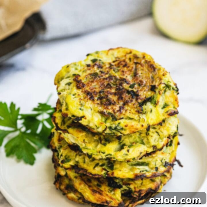 Crispy zucchini fritters on a plate with a side of yogurt dip.