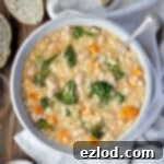 Velvety Vegan Pearl Couscous Soup 11 A bowl of creamy pearl couscous soup on a wooden table with a sliced loaf of bread.