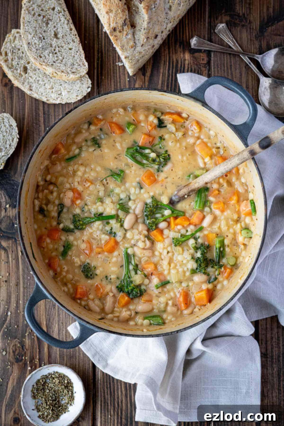 Velvety Vegan Pearl Couscous Soup 9 Step 5 in making creamy pearl couscous soup: the finished soup in a pan on a wooden table, ready to be served.