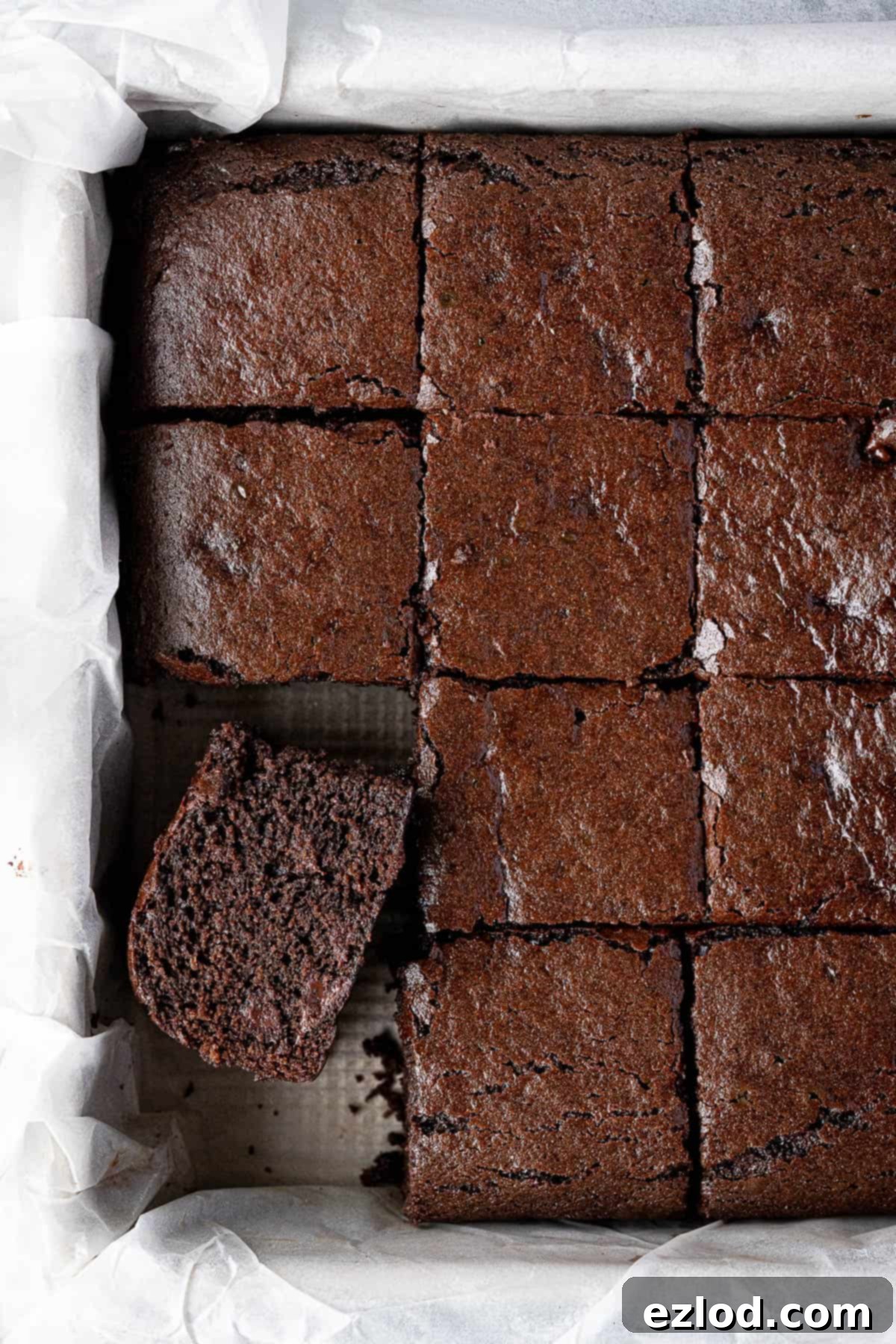 Decadent Vegan Chocolate Gingerbread Cake 2 Sliced vegan chocolate gingerbread in a parchment lined tin, showing its moist texture and chocolate chips.