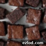 Decadent Vegan Chocolate Gingerbread Cake 11 Squares of vegan chocolate gingerbread on a sheet of baking parchment.