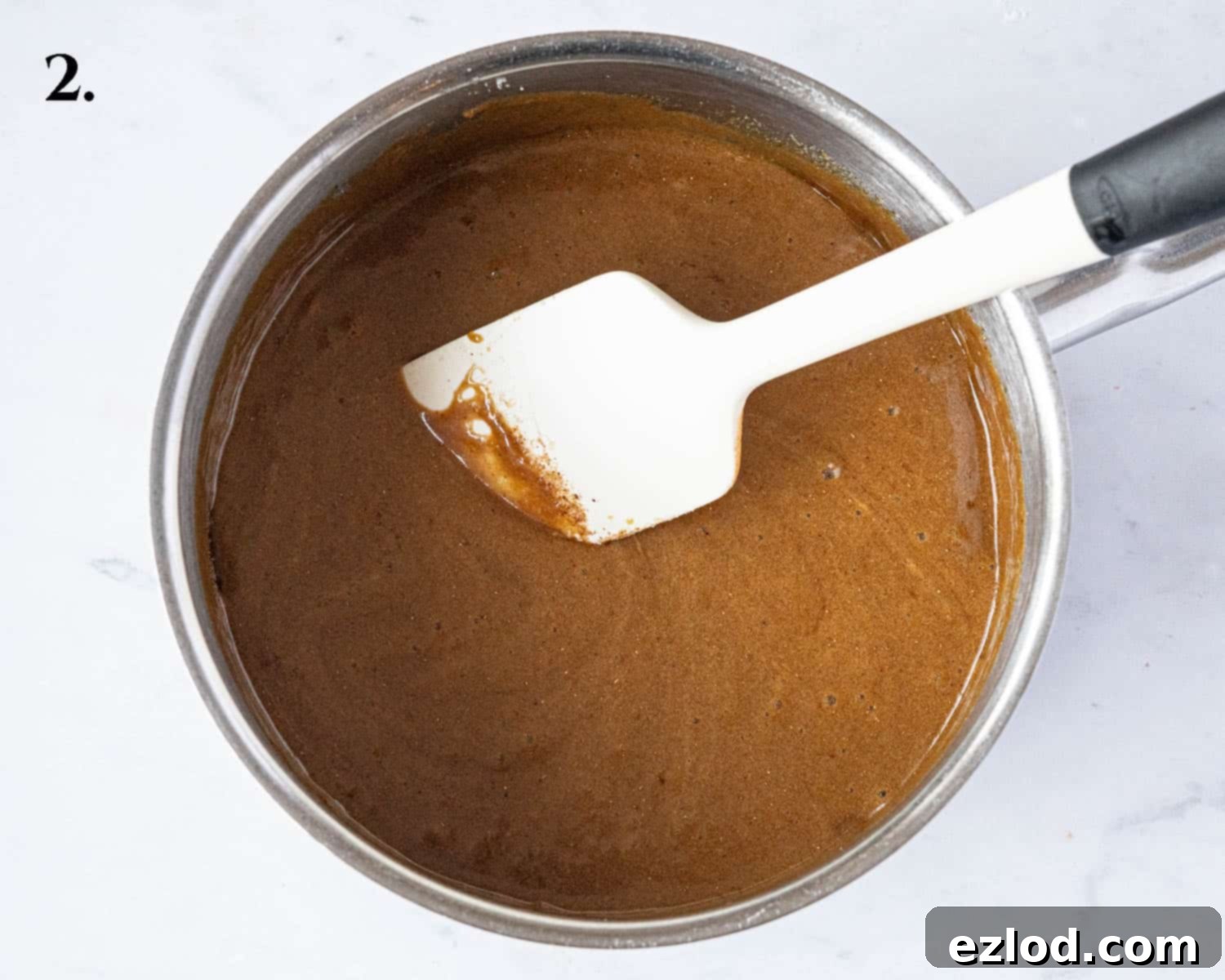 The wet ingredients in a pan after the spices, baking powder, and bicarbonate of soda have been whisked in, showing a slight foamy texture.