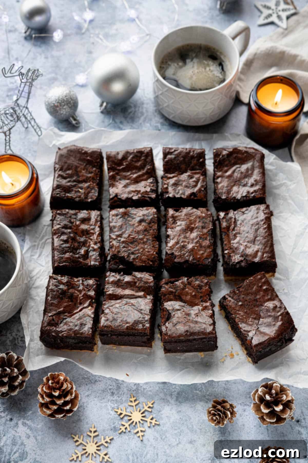 Festive Vegan Mince Pie Brownies 14 The sliced brownies on a sheet of baking paper surrounded by candles, mugs of coffee and Christmas ornaments.