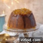 Steamed gingerbread pudding on a glass cake stand with Christmas lights and decorations.