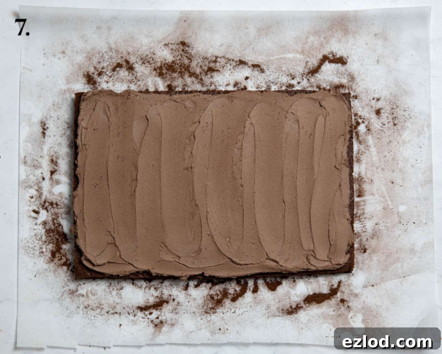 Plant-Based Chocolate Yule Log 11 Step 7: The cake layer is completely covered with a smooth, even layer of chocolate buttercream, spread using a palette knife.